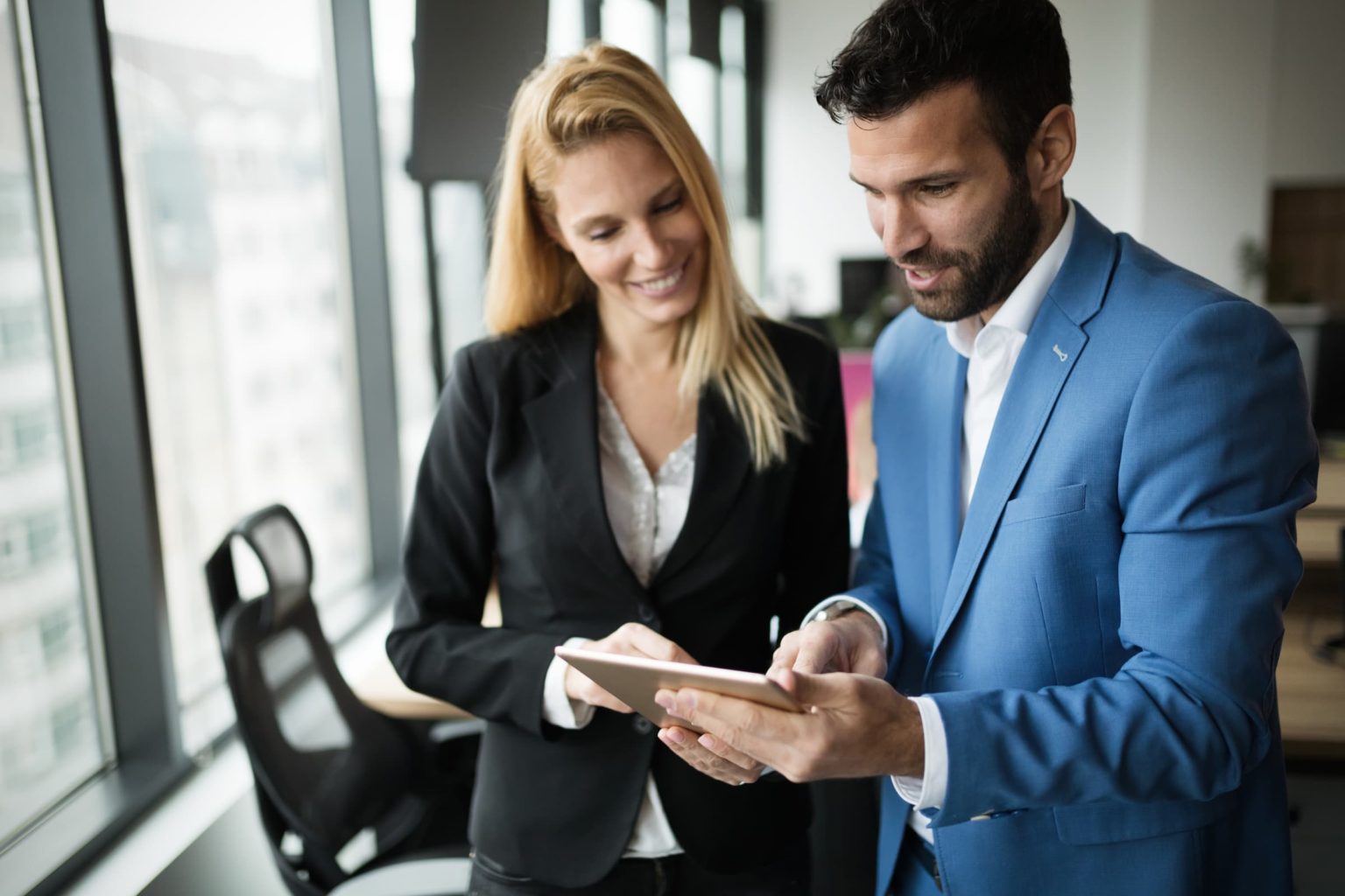 Businesspeople discussing while using digital tablet in office together